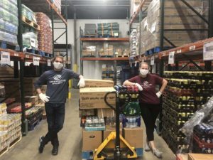 Two staff members with a pallet of food to deliver to families.