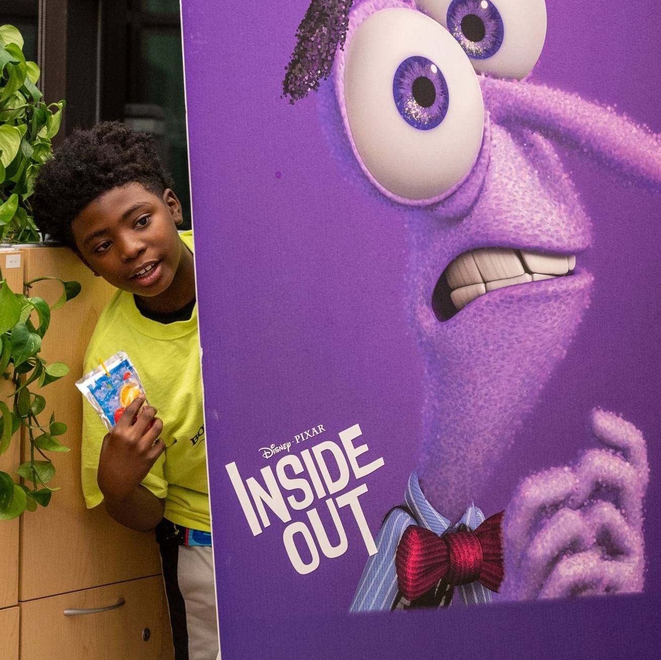 Club member peaks out from behind a poster featuring an Inside Out character during an InsideU pilot event.